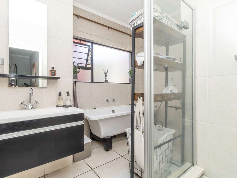 A well-maintained bathroom featuring a freestanding bathtub, a separate glass-enclosed shower, and a modern wall-mounted vanity with a basin.