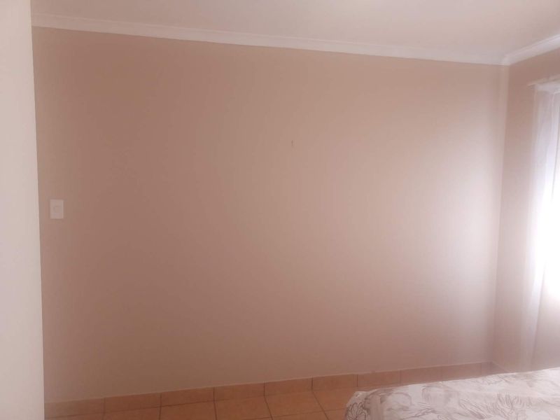 A simple, neutral-toned bedroom featuring tiled flooring and cove cornicing, offering a blank canvas for personalization.