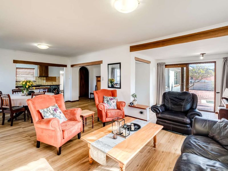 Spacious open-plan living and dining area featuring light laminate flooring, exposed timber beams, and direct access to the outdoor patio through sliding glass doors.
