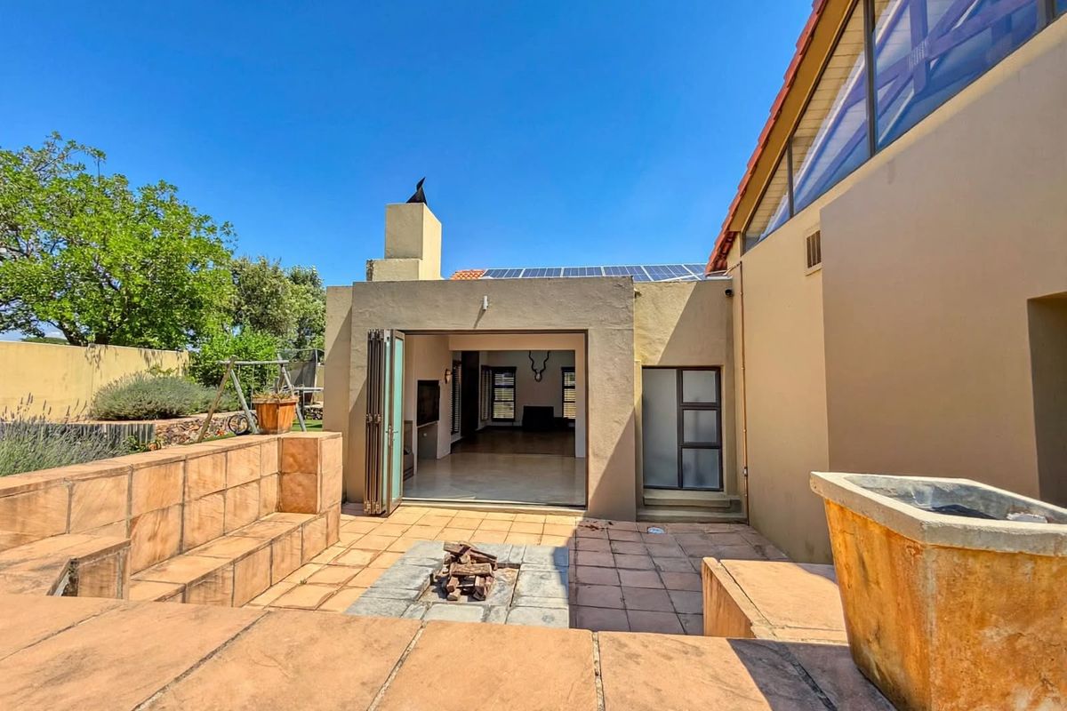 Rear patio area featuring a built-in fire pit, tiled flooring, and bi-fold doors providing seamless access to the interior living space.