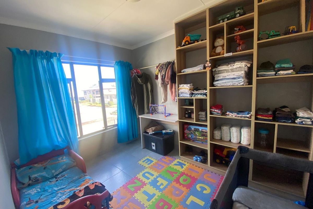 A bedroom featuring built-in floor-to-ceiling shelving units and tiled flooring, providing ample storage space and natural light through the window.