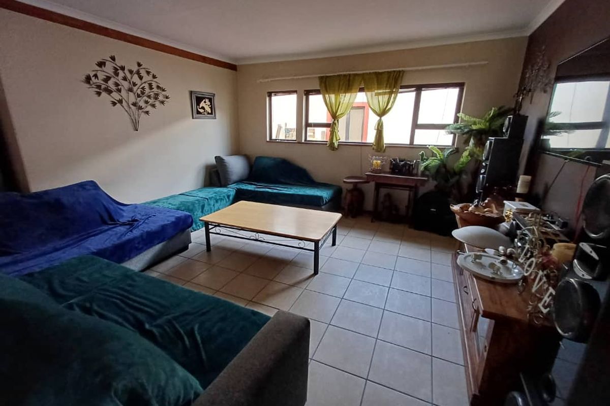 A living room featuring tiled flooring and large windows, providing a functional and comfortable space for relaxation.