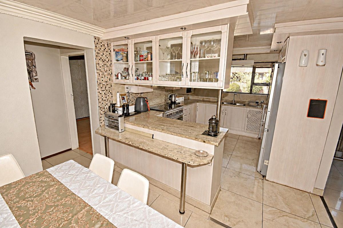 A functional kitchen featuring granite countertops, a breakfast bar, glass-front cabinetry, and tiled flooring, offering a practical layout for cooking and dining.
