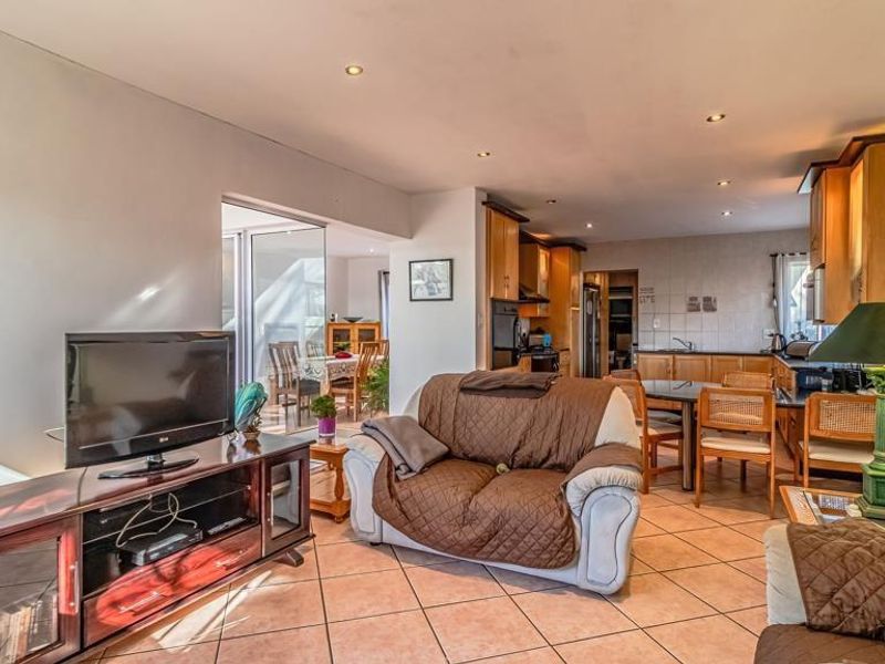 Spacious open-plan living and kitchen area featuring tiled flooring, recessed lighting, and direct access to an outdoor patio through sliding glass doors.