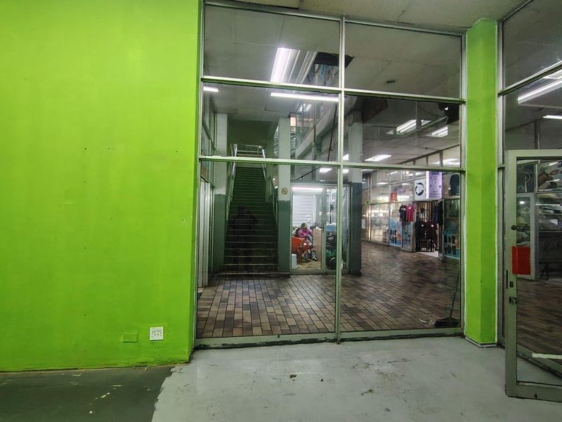 Commercial entry area featuring a glass storefront, tiled flooring, and an internal staircase leading to upper levels.