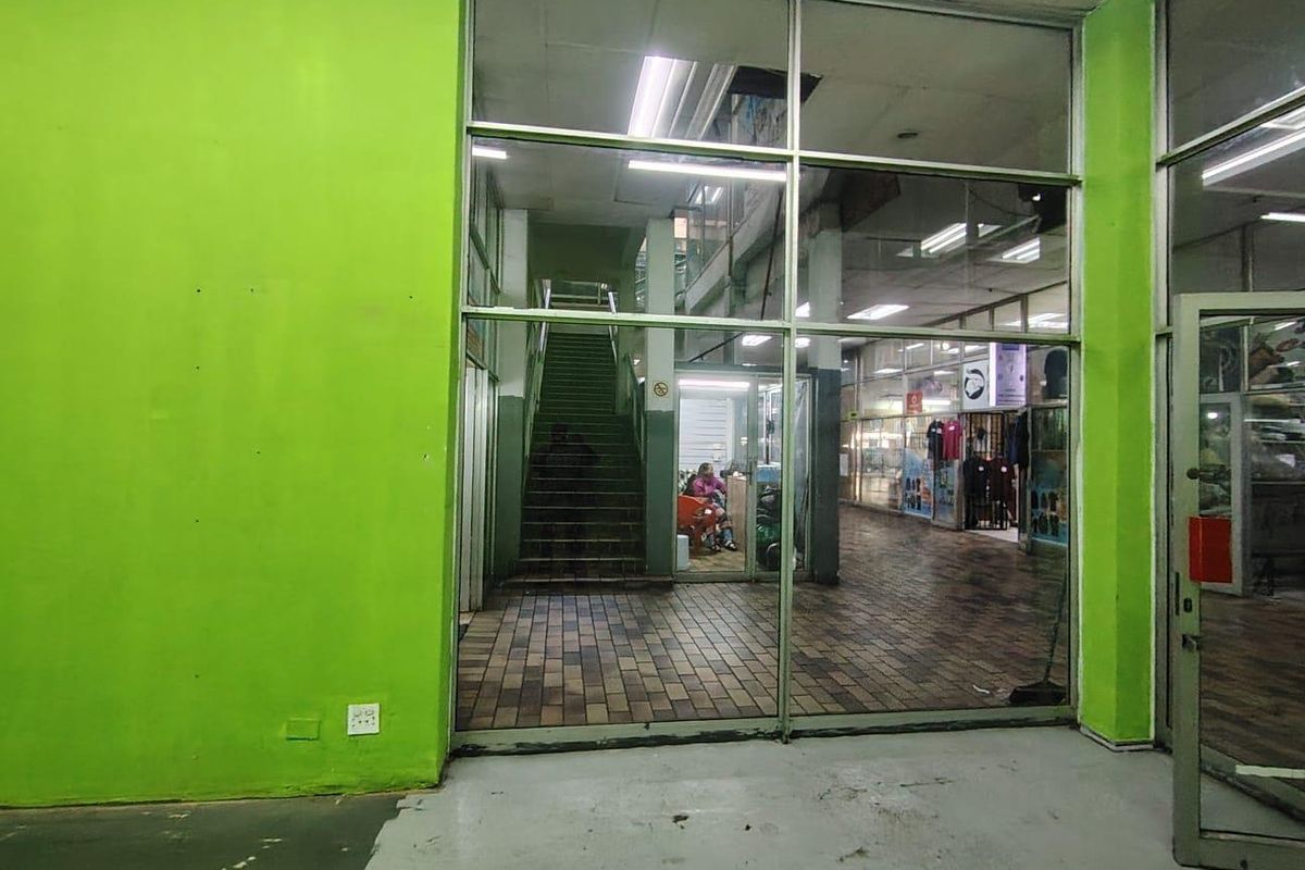 Commercial entry area featuring a glass storefront, tiled flooring, and an internal staircase leading to upper levels.