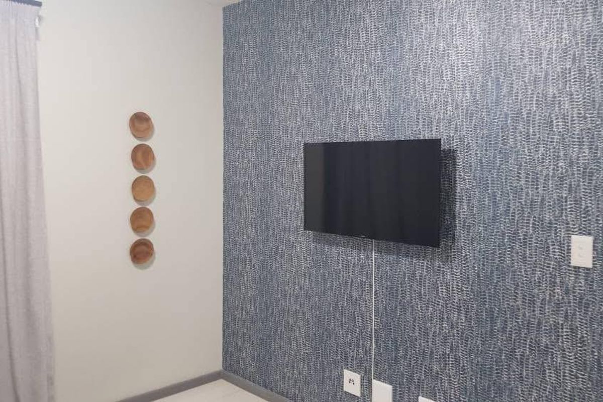 A bedroom featuring a blue textured accent wall, neutral flooring, and wall-mounted television point.