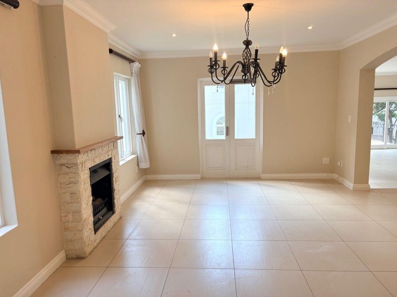 Spacious living area featuring tiled flooring, a stone-clad fireplace, and double glass doors leading to an outdoor space.