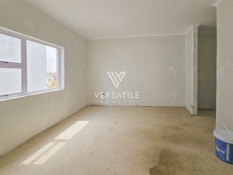 An empty, unfinished living room space featuring bare concrete floors and walls requiring final plastering and painting, offering a blank canvas for renovation.