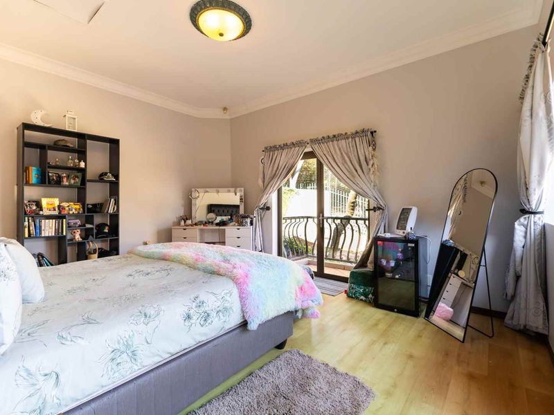 Spacious bedroom featuring laminate flooring, neutral walls, and a sliding glass door providing direct access to a private balcony.