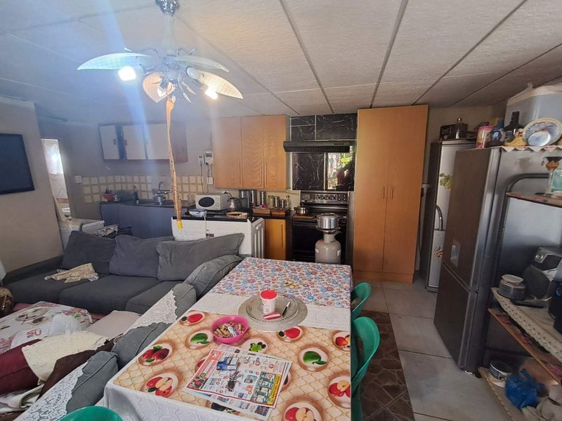 Open-plan living and kitchen area featuring built-in cabinetry, a stove with extractor fan, and tiled flooring, offering a functional layout for daily living.