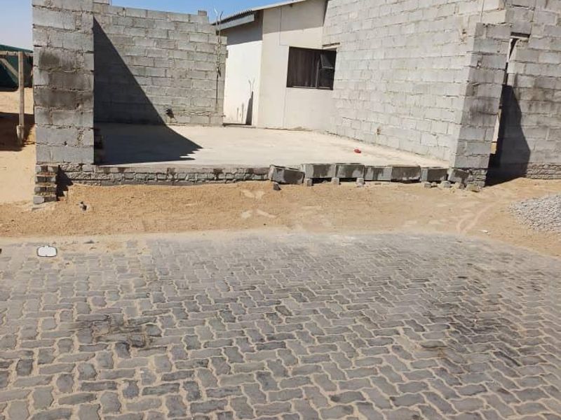 An unfinished residential property exterior featuring exposed concrete block walls and a paved driveway, currently under construction.