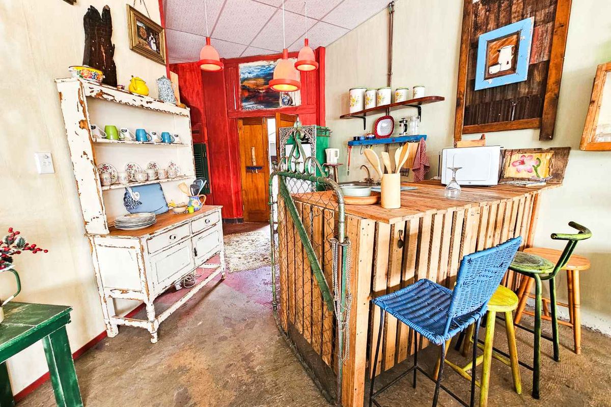 A rustic kitchen area featuring a custom timber breakfast bar, open shelving, and unique decorative elements with a distinct eclectic aesthetic.