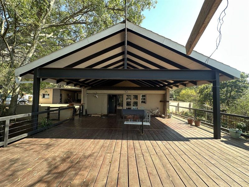 Spacious covered outdoor patio featuring timber decking, exposed steel structural beams, and a pitched roof, offering an ideal area for outdoor entertaining.