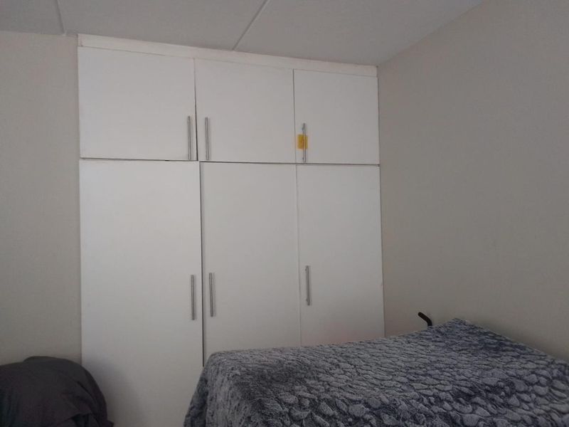 A bedroom featuring floor-to-ceiling built-in white cabinetry with modern handles, providing ample storage space.