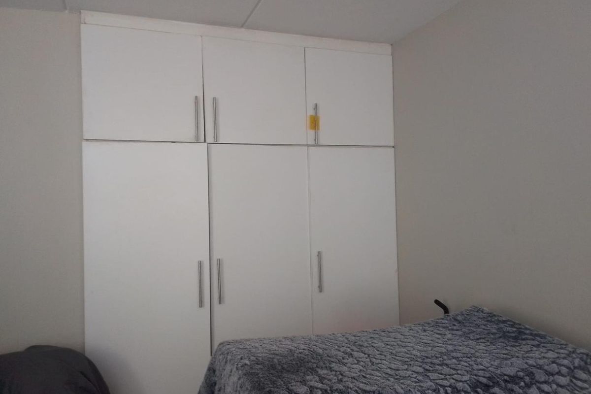 A bedroom featuring floor-to-ceiling built-in white cabinetry with modern handles, providing ample storage space.