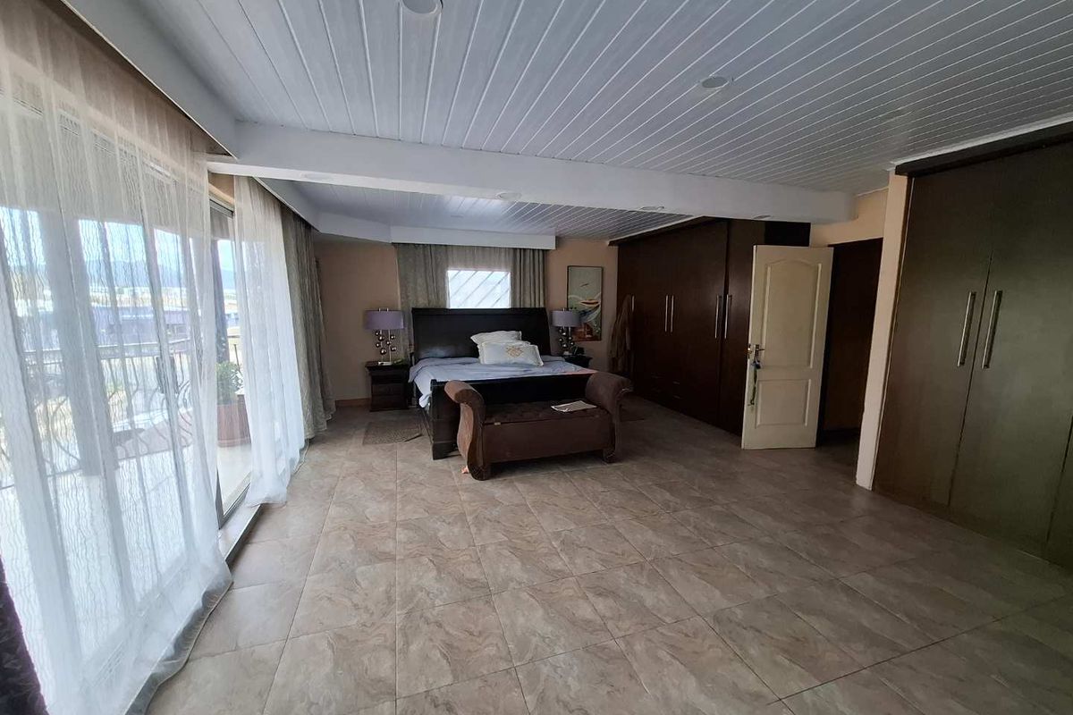 Spacious bedroom featuring large sliding glass doors, built-in wooden wardrobes, and tiled flooring with direct access to an outdoor balcony area.