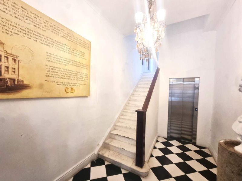 Entrance foyer featuring a classic staircase, stainless steel elevator, and decorative chandelier with traditional checkered tile flooring.