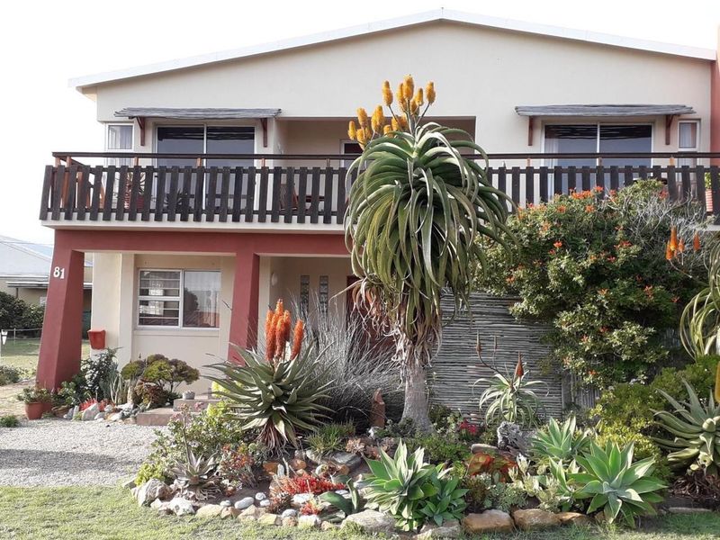 A two-story residential property featuring a balcony, established succulent garden, and paved driveway area.