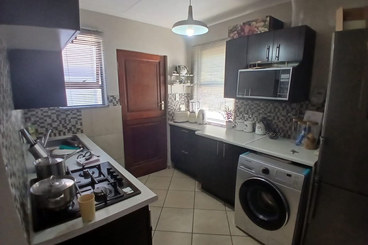 Functional kitchen featuring dark cabinetry, gas hob, built-in microwave, tiled backsplash, and tiled flooring with direct access to an exterior door.