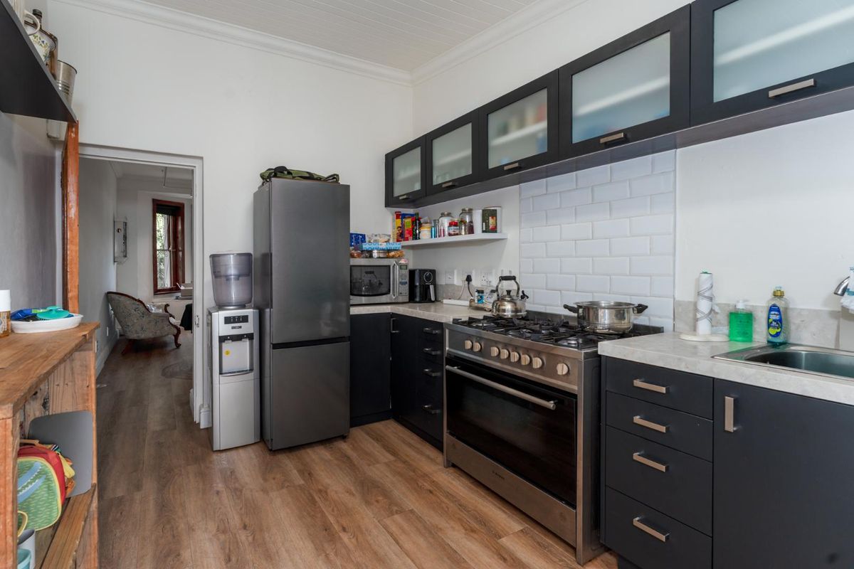 A functional kitchen featuring dark cabinetry, a gas stove with oven, subway tile backsplash, and wood-look laminate flooring.