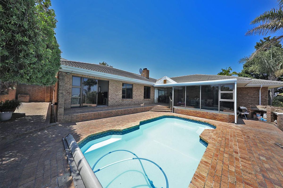 Rear exterior view featuring a brick-clad house, a swimming pool with a paved surround, and an enclosed patio area.