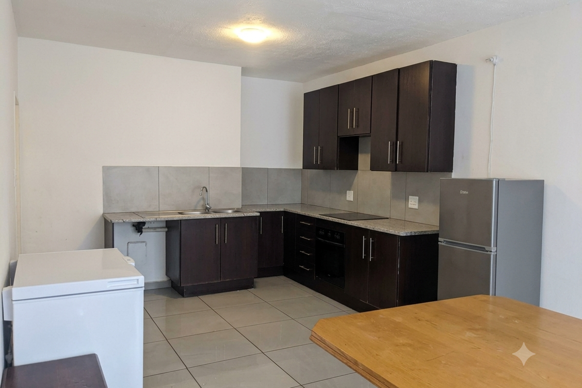 A functional kitchen featuring dark wood cabinetry, granite countertops, a built-in oven, electric hob, and tiled flooring.