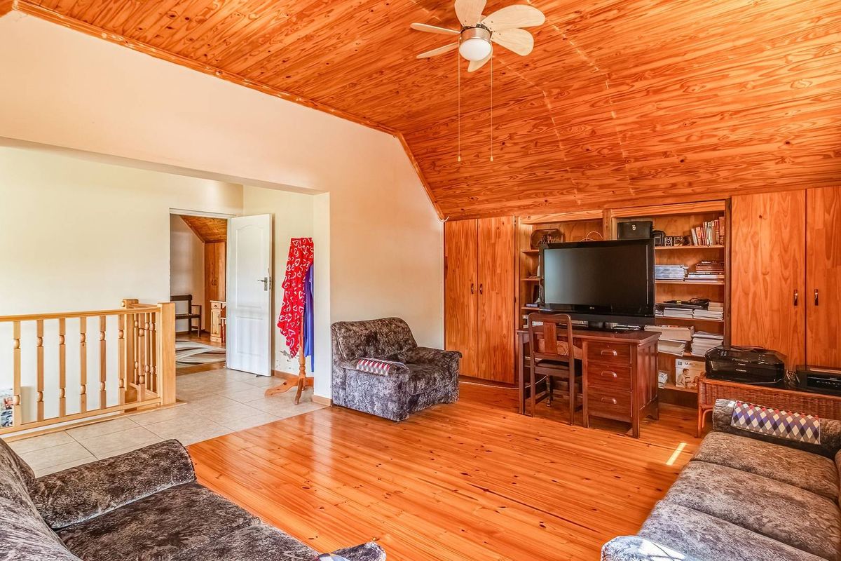 Spacious living area featuring warm timber flooring, a vaulted timber ceiling, built-in cabinetry, and a timber balustrade overlooking the lower level.