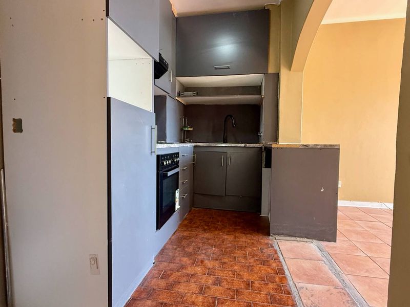 A compact kitchen area featuring built-in cabinetry, an integrated oven, and a sink, currently requiring finishing touches and cosmetic updates.