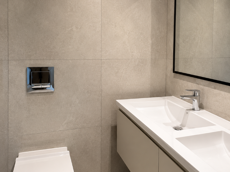 Modern bathroom featuring a floating double vanity, wall-mounted toilet with chrome flush plate, and large format neutral porcelain wall tiles.