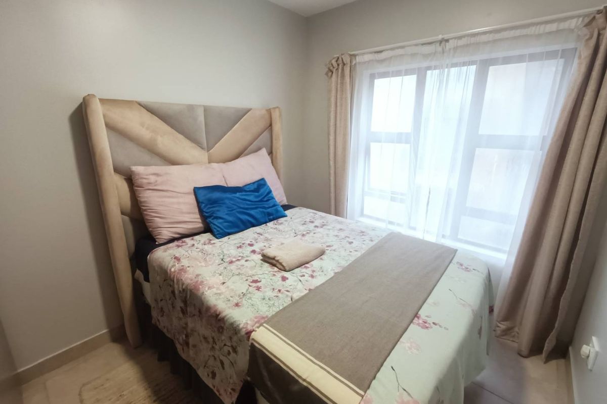 A well-maintained bedroom featuring neutral wall tones, tiled flooring, and a large window that allows for natural light.