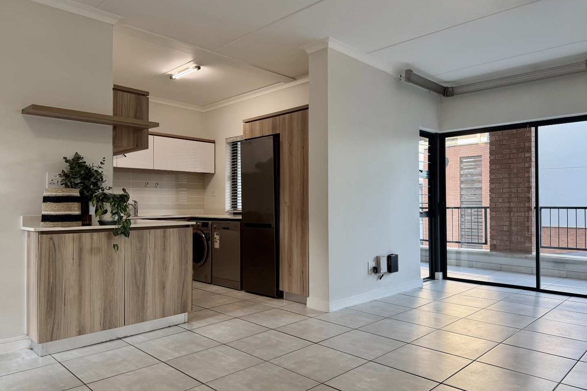 Open-plan living area featuring modern wood-finish cabinetry, tiled flooring, and a sliding glass door leading to a balcony.