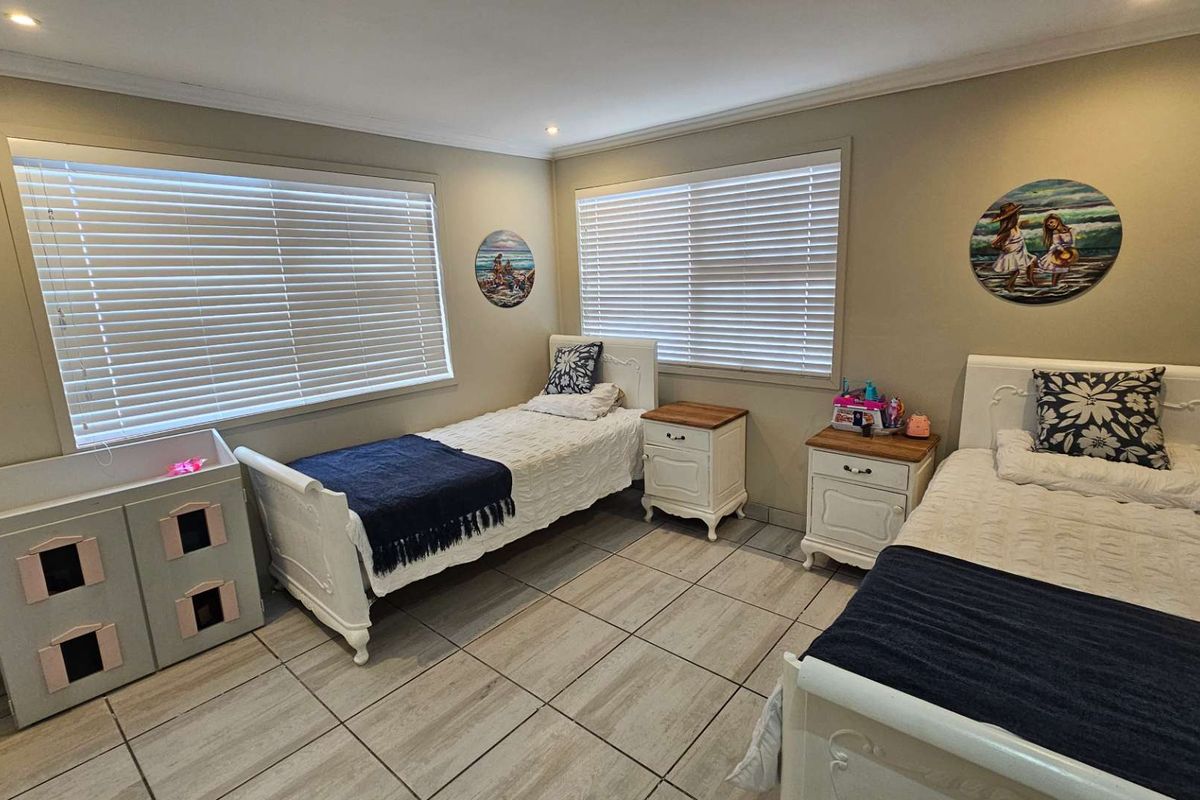 A well-maintained bedroom featuring tiled flooring, dual windows with fitted blinds, and recessed ceiling lighting.