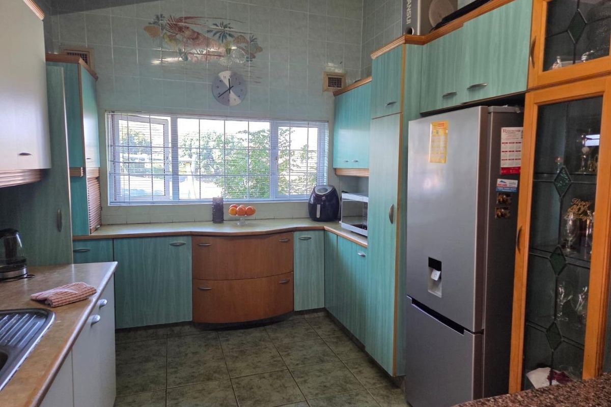 A dated kitchen featuring laminate cabinetry, tiled splashbacks, and tiled flooring, offering a functional layout with potential for modern renovation.