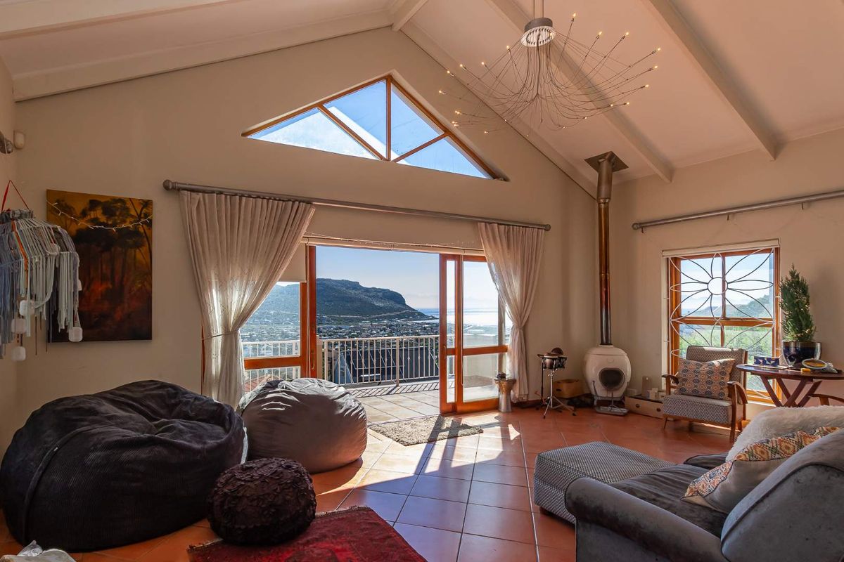Spacious living room featuring a vaulted ceiling with exposed beams, a freestanding fireplace, and large sliding doors opening to a balcony with scenic views.