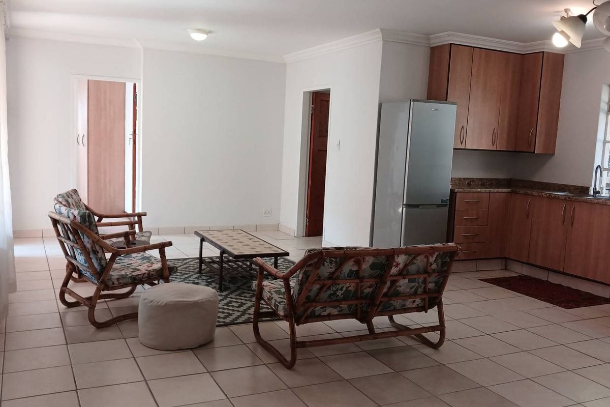 Open-plan living and kitchen area featuring tiled flooring, laminate cabinetry with granite countertops, and neutral wall finishes.