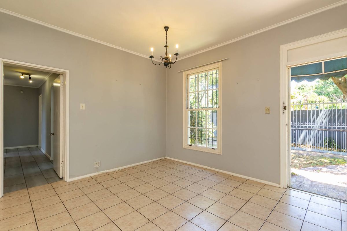 A bright, empty living area featuring tiled flooring, a classic chandelier, and direct access to an outdoor patio space.