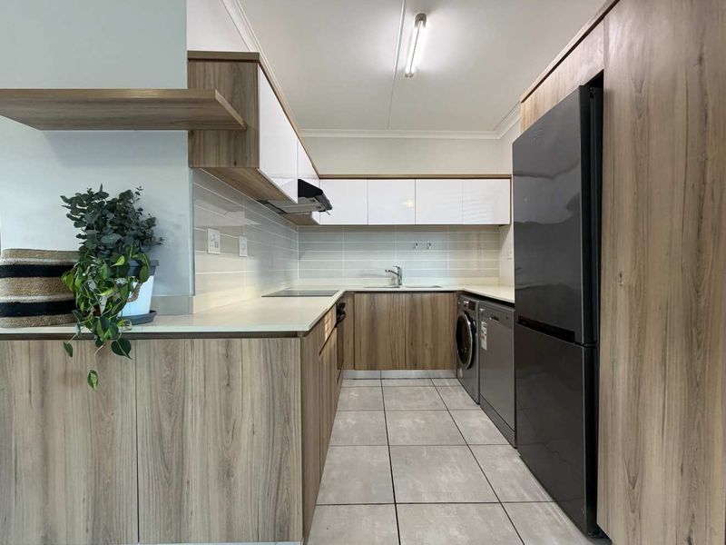 Modern kitchen featuring wood-grain cabinetry, white high-gloss upper cabinets, stone countertops, tiled backsplash, and integrated appliance spaces with neutral floor tiling.