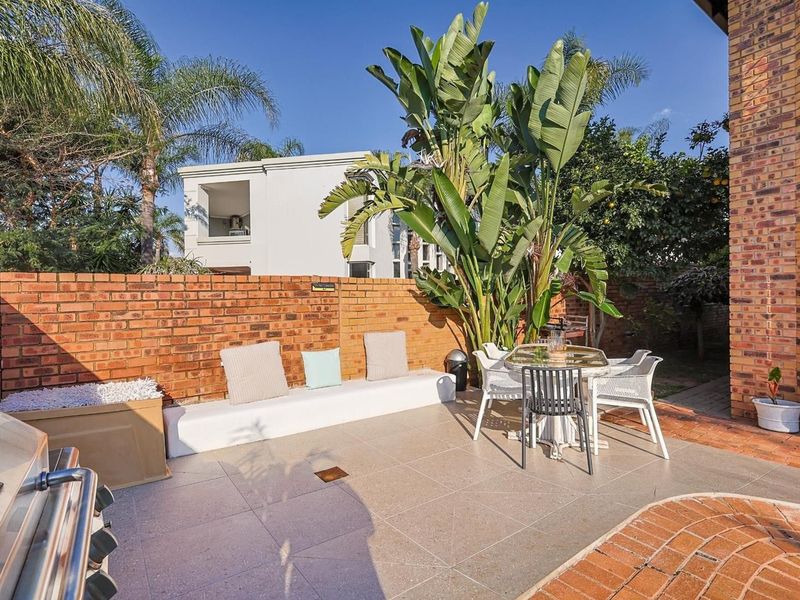 A private outdoor patio area featuring a built-in brick wall, tiled flooring, and integrated bench seating, perfect for outdoor dining and relaxation.