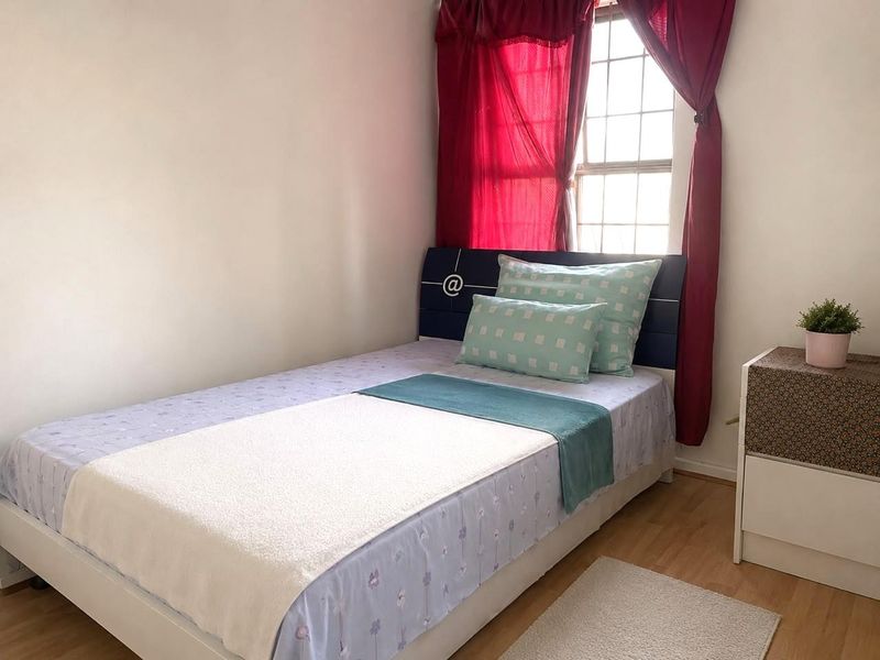 A functional bedroom featuring laminate flooring and a grid-pattern window, providing natural light to the space.