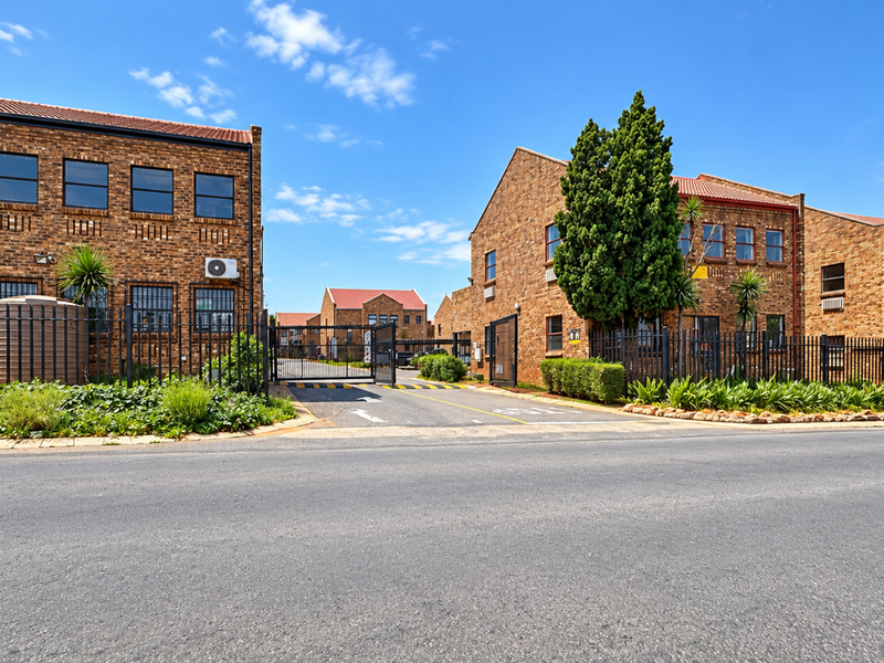 A professional exterior view of a commercial office park featuring face brick buildings, secure gated access, and well-maintained landscaping.