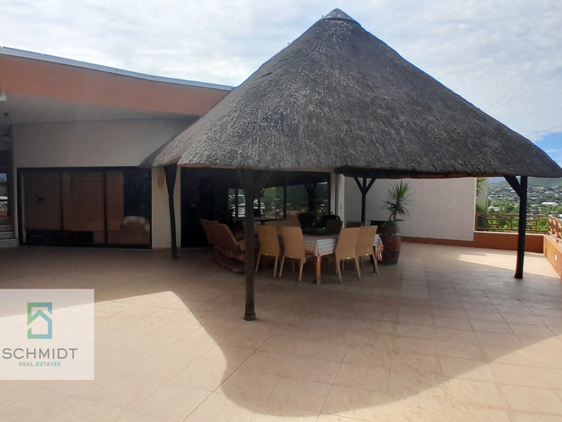 Spacious covered patio featuring a traditional thatched roof, tiled flooring, and a wooden balustrade overlooking the surrounding landscape.
