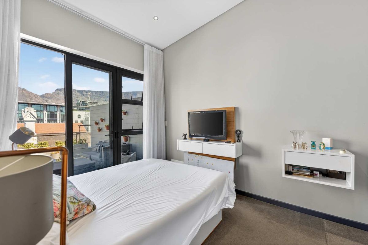 Modern bedroom featuring neutral tones, wall-mounted storage units, and large sliding glass doors providing access to a private balcony with mountain views.