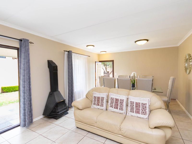 Open-plan living and dining area featuring tiled flooring, a freestanding fireplace, and direct access to the garden through a sliding glass door.