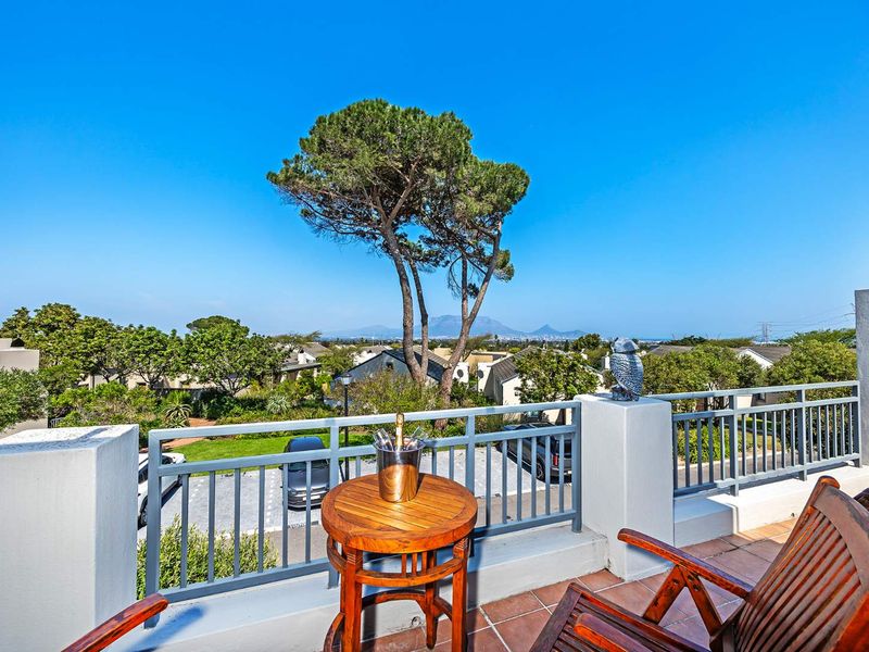 A spacious balcony featuring tiled flooring and metal railings, offering elevated views of the surrounding neighborhood and distant mountain landscape.