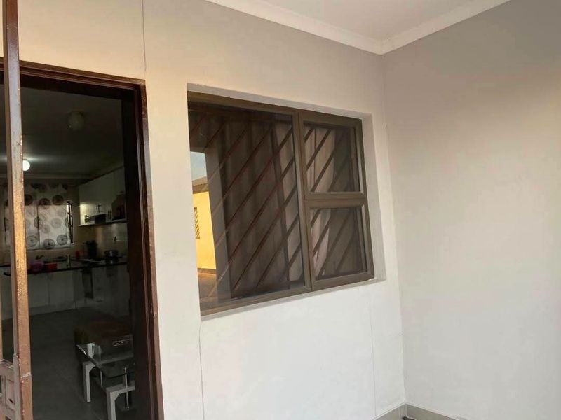 A covered patio area featuring security bars on the window and a clear view into the adjacent kitchen space.