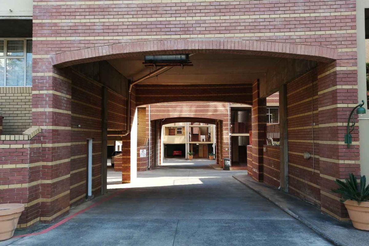 A view of the apartment complex entrance featuring a brick facade with arched drive-through access and concrete driveway.