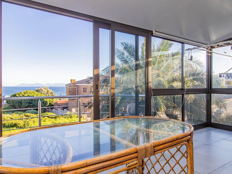 Enclosed balcony featuring tiled flooring, sliding glass doors, and expansive ocean views, providing a versatile outdoor living space.