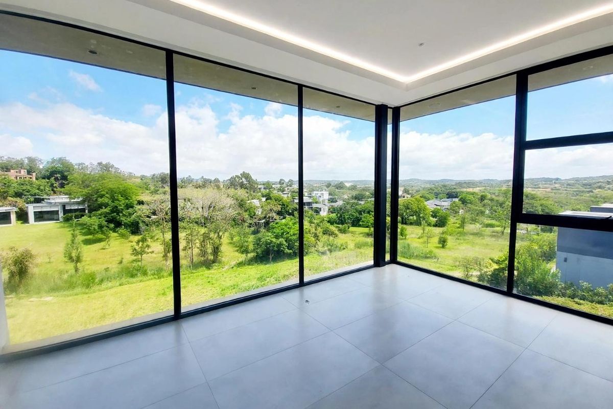 A bright, modern, empty living space featuring expansive floor-to-ceiling windows that offer panoramic views of the surrounding landscape.