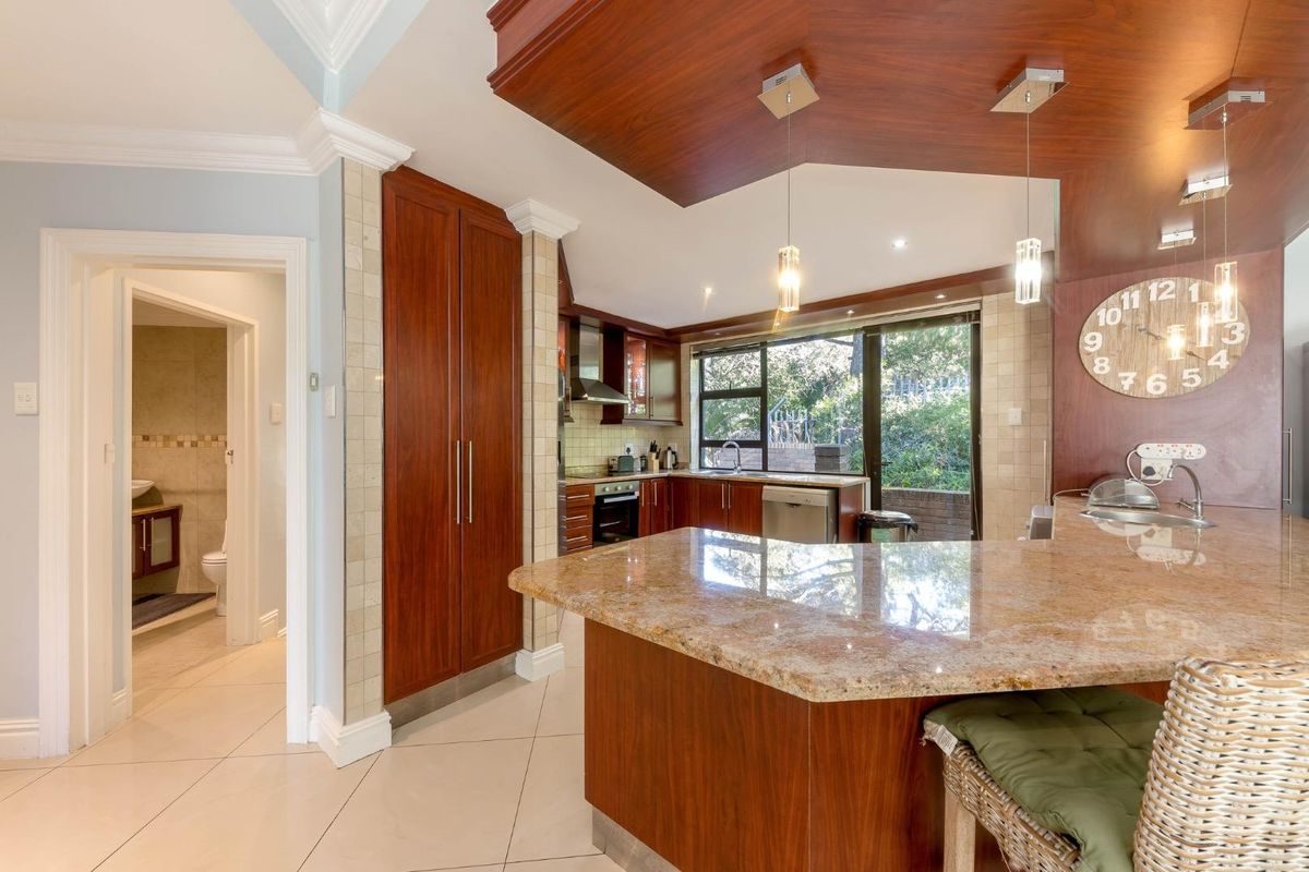 A well-appointed kitchen featuring rich wooden cabinetry, granite countertops, and integrated appliances, with a seamless flow into the adjacent living area.